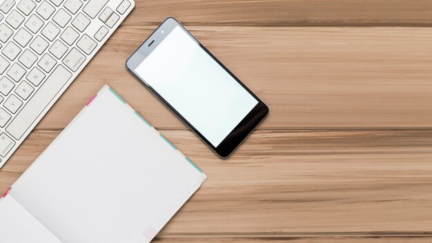 Pose créative de bureau en bois au travail avec clavier et mobile