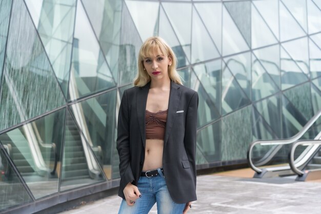 Pose à La Mode D'une Jeune Blonde Dans Des Bâtiments En Verre De La Ville Photo Premium