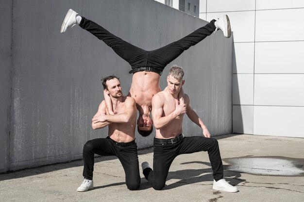 Pose de trois danseurs de hip hop torse nu à l'extérieur