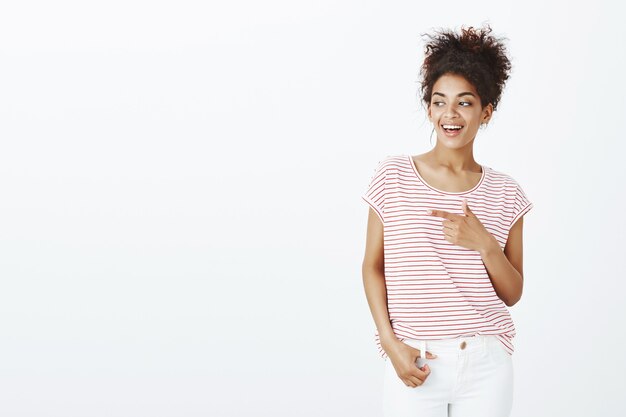 Positive belle femme avec une coiffure afro posant dans le studio