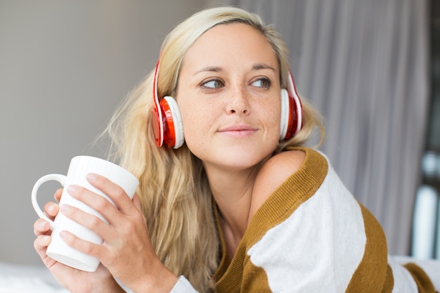 Positive jeune femme dans le casque tenant la tasse