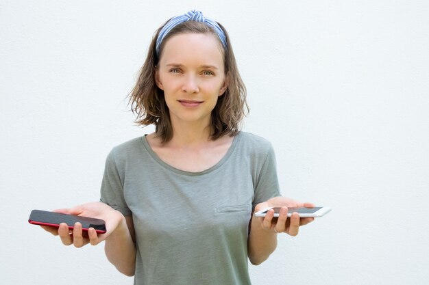 Positive jeune femme en vêtements d'été tenant des téléphones