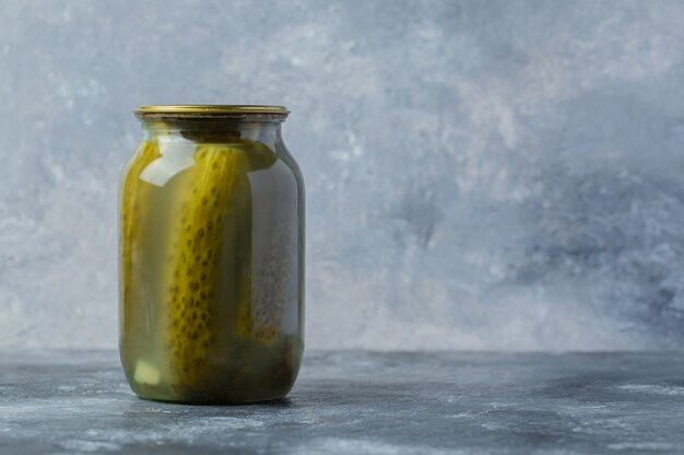 Un pot de cornichon sur une table grise. Saisonnier.