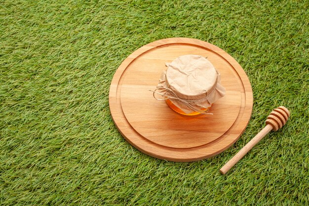 Pot avec du miel fait maison sur une planche de bois