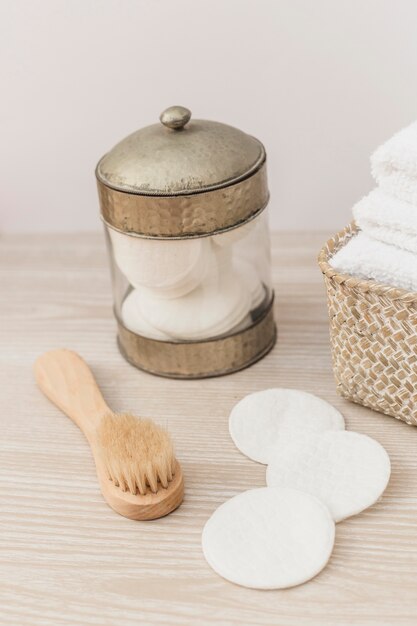 Pot d&#39;éponge; brosse et serviettes dans le panier sur une surface en bois