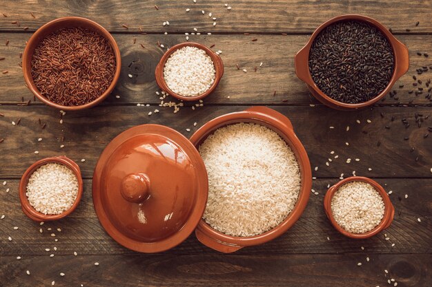 Un pot de grains de riz bio avec des bols sur une table en bois