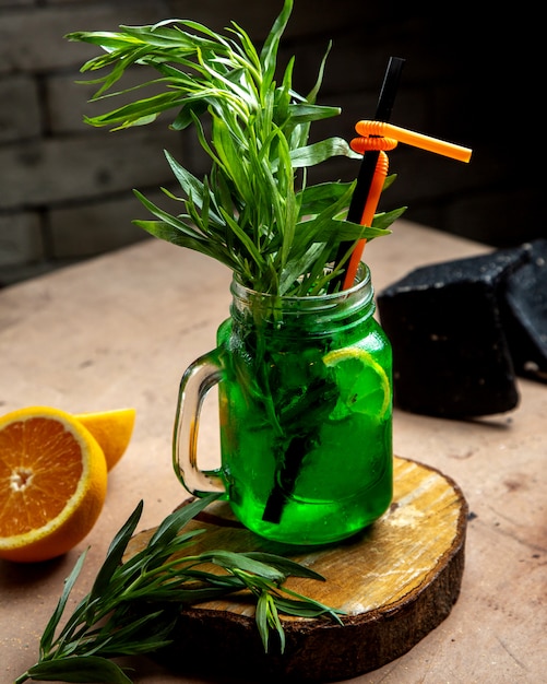 Un pot Mason avec une boisson à l'estragon garnie d'estragon et d'une tranche de citron