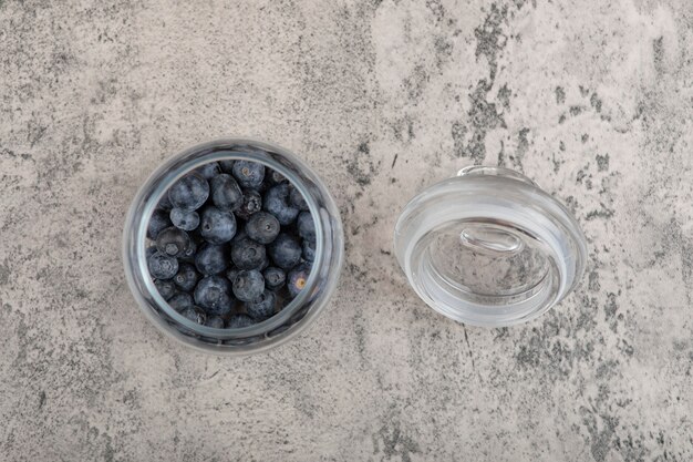 Pot en verre de bleuets frais délicieux sur une surface en marbre