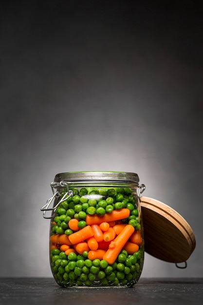 Pot en verre avec petits pois et carottes miniatures