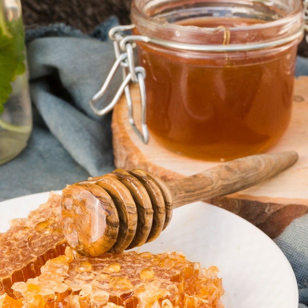 Pot en verre plein de miel avec une cuillère à miel