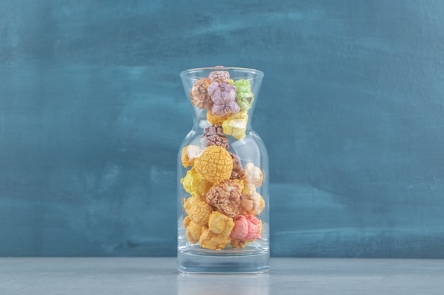 Un pot en verre de pop-corn multicolore sucré.