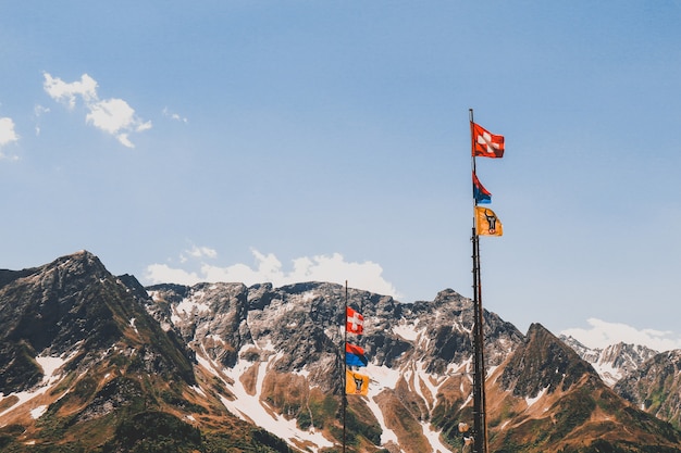 Poteaux avec des drapeaux dans les belles montagnes rocheuses couvertes de neige sous le ciel nuageux