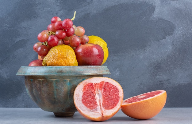 Une poterie pleine de fruits frais bio. Sur fond gris.