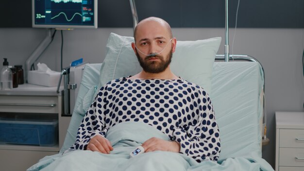 Potrait d'homme malade hospitalisé avec tube nasal à oxygène souffrant de troubles respiratoires