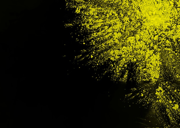 Photo gratuite poudre de holi jaune sur le coin de la surface noire