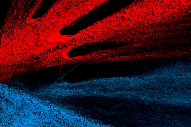 Poudre de holi rouge et bleu vif contre une surface noire