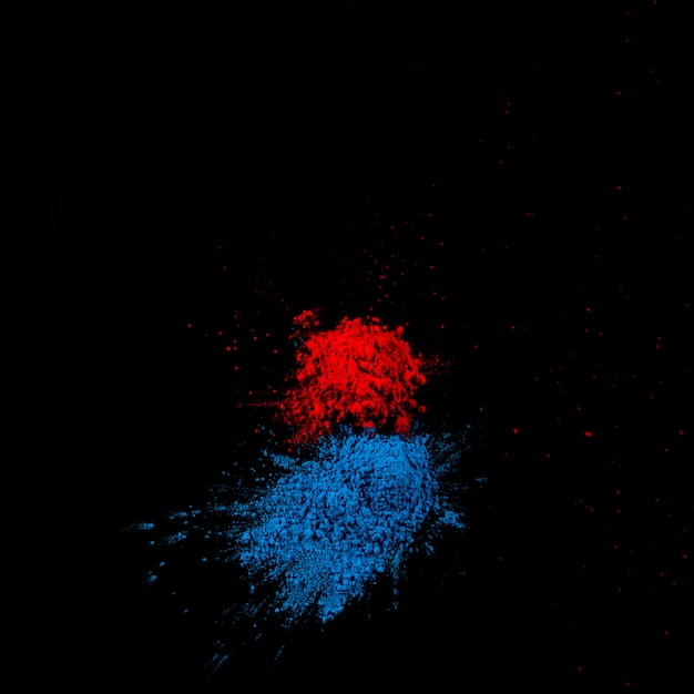 Poudre de holi rouge et bleue sur une surface noire
