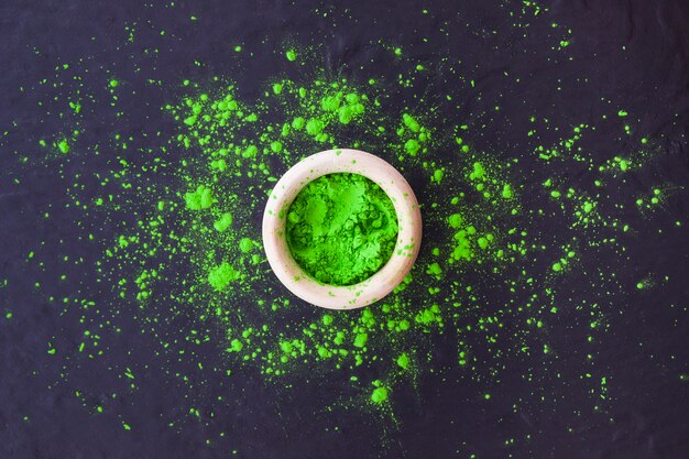 Poudre de holi vert dans un bol sur fond texturé