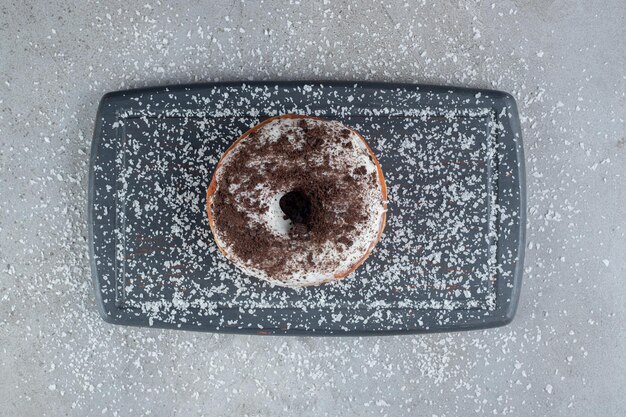 Poudre de noix de coco saupoudrée autour d'un beignet sur un plateau sur une surface en marbre