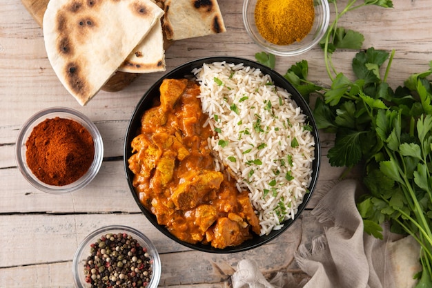 Poulet au beurre indien dans un bol noir sur une table en bois