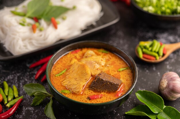 Poulet au curry dans une tasse noire avec des nouilles de riz.