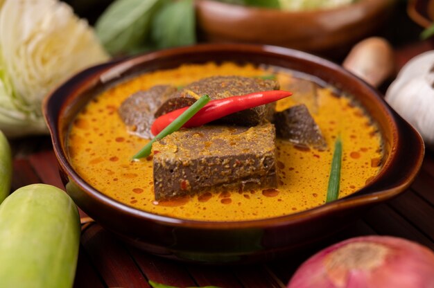 Poulet au curry sanguin dans un bol avec piment, oignons nouveaux, concombre et oignon rouge