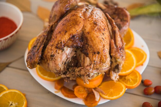 Poulet au four avec des oranges sur une table lumineuse