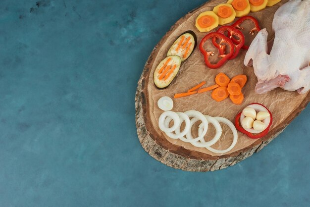 Un poulet aux légumes sur une planche de bois.