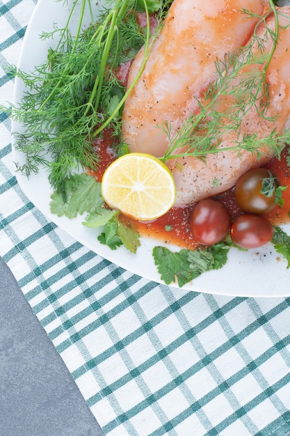 Poulet entier mariné sur assiette avec légumes.