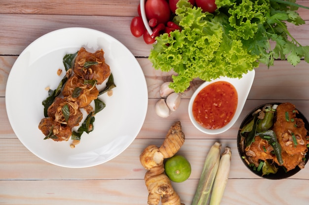 Poulet frit aux herbes sur une plaque blanche sur un plancher en bois.