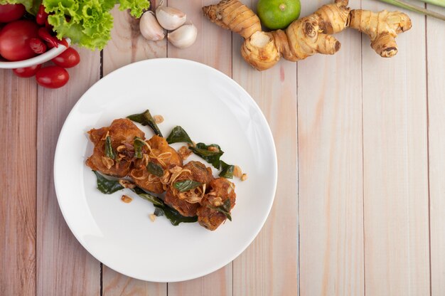 Poulet frit aux herbes sur une plaque blanche sur un plancher en bois.