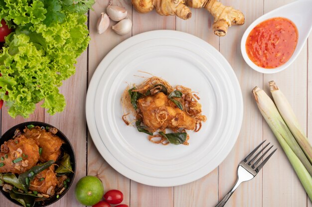 Poulet frit aux herbes sur une plaque blanche sur un plancher en bois.