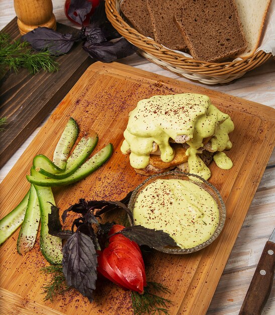 Poulet frit, filet de poisson avec fromage fondu et tomates, salade de concombre sur une planche de bois