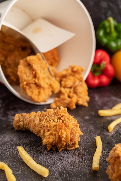 Poulet frit et frites sur un sol en ciment noir.