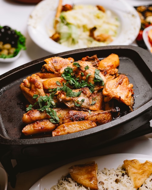 Poulet frit avec pomme de terre dans la casserole vue de côté verts