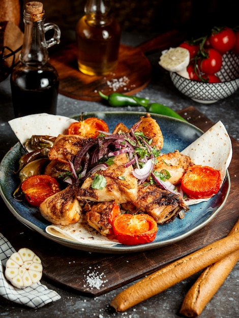 Poulet frit avec des tranches de tomate et des oignons