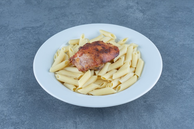 Poulet grillé et pâtes penne dans un bol blanc.