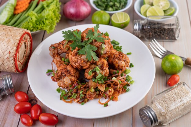 Poulet haché épicé sur une assiette blanche avec concombre, laitue et accompagnements.