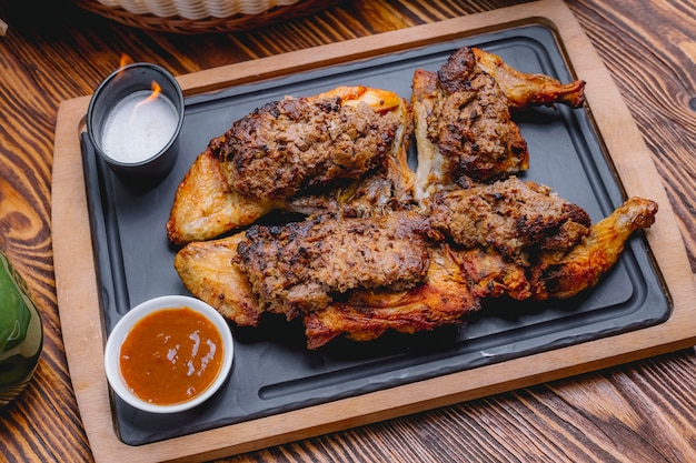 Poulet lavangi sur planche de bois noix oignon prune vue latérale