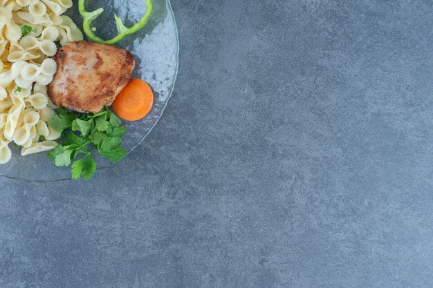 Poulet rôti et pâtes savoureuses sur plaque de verre.