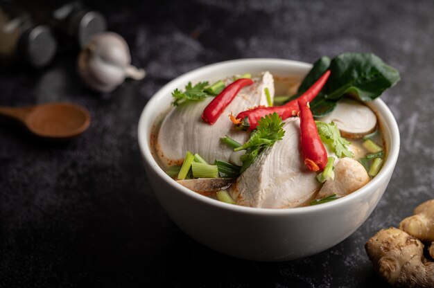 Poulet Tom yum avec chili, coriandre, piment séché, feuilles de lime kaffir, champignons et citronnelle dans un bol