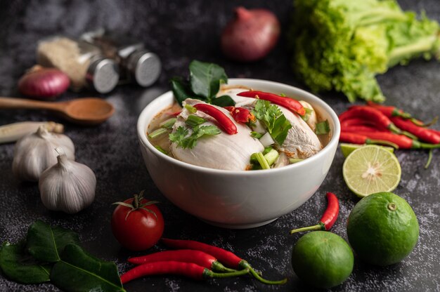 Poulet Tom yum avec chili, coriandre, piment séché, feuilles de lime kaffir, champignons et citronnelle dans un bol