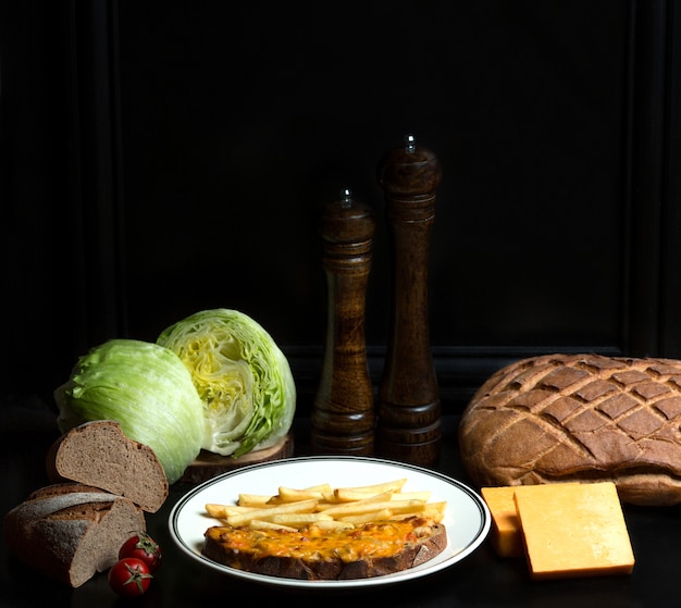 Poulet et tomates garnies de fromage râpé sur du pain et des frites