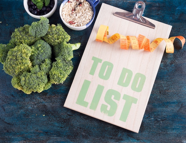 Photo gratuite pour faire la liste avec le brocoli et le ruban à mesurer sur la table