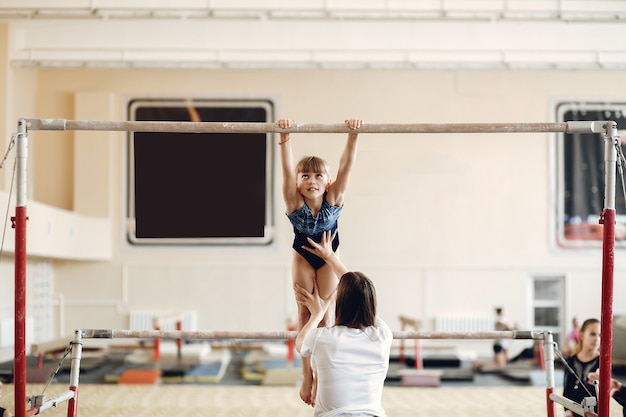 Poutre de gymnastique enfant. Athlète gymnaste fille lors d'un exercice barre horizontale dans les compétitions de gymnastique. Coach avec enfant.