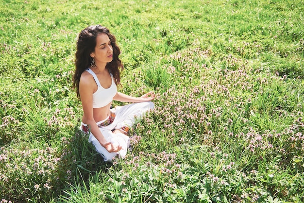 Pratiquer le yoga d'une belle fille le matin sur des herbes sous les mots du soleil.