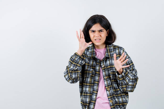 Préadolescente en chemise, veste levant les mains pour se défendre et avoir l'air agressif, vue de face. espace pour le texte