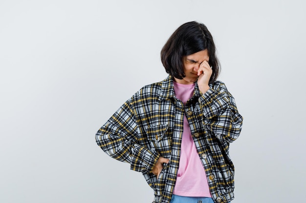 Préadolescente se frottant un œil en chemise, veste et à la somnolence, vue de face.