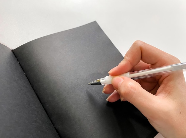 Prendre des notes à la main dans un cahier avec un concept de planification de feuilles noires