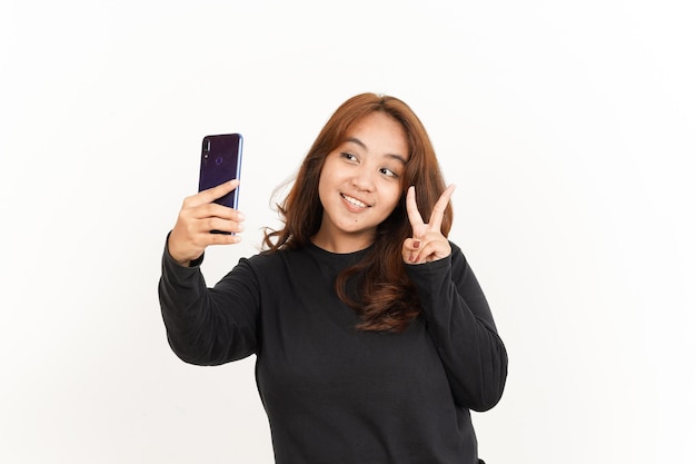 Prenez un selfie avec un smartphone de la belle femme asiatique portant une chemise noire isolée sur blanc